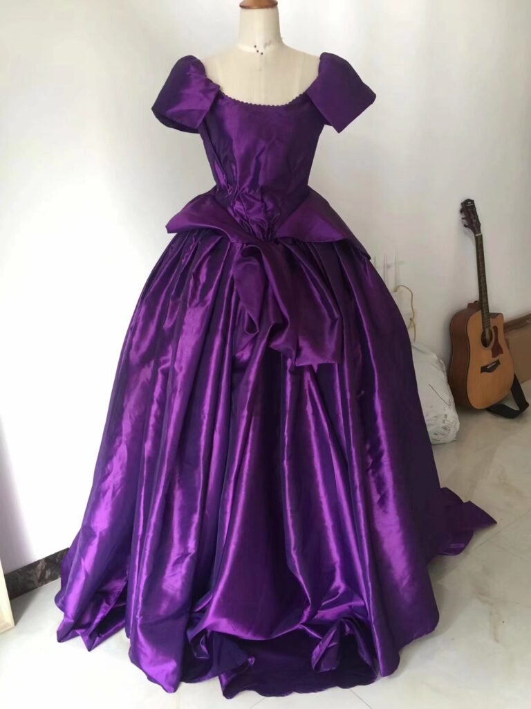 Front view of purple custom wedding dress with off-shoulder sleeves and large waist bow on mannequin