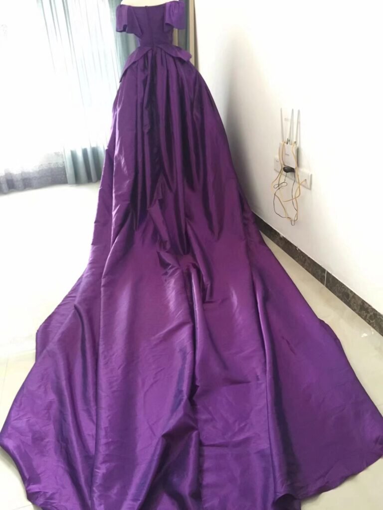 Purple custom wedding dress back view showing dramatic train and bow detail on a mannequin